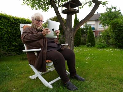 Seniorin mit iPad / Ob E-Mails oder Fotos - mit dem iPad kann sich die 67-J&auml;hrige auch in ihrem Garten informieren. F&uuml;r sie ist das iPad einfacher zu bedienen als ein Laptop. (Bild: dpa)